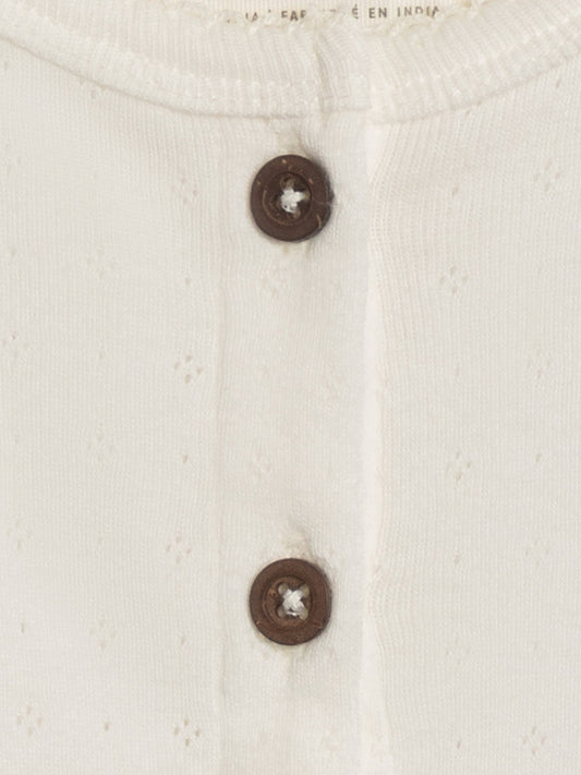 Close-up of a white textured fabric with two brown buttons.