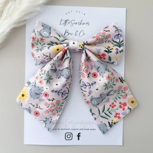 Floral bow hair clips on a branded card with a soft background