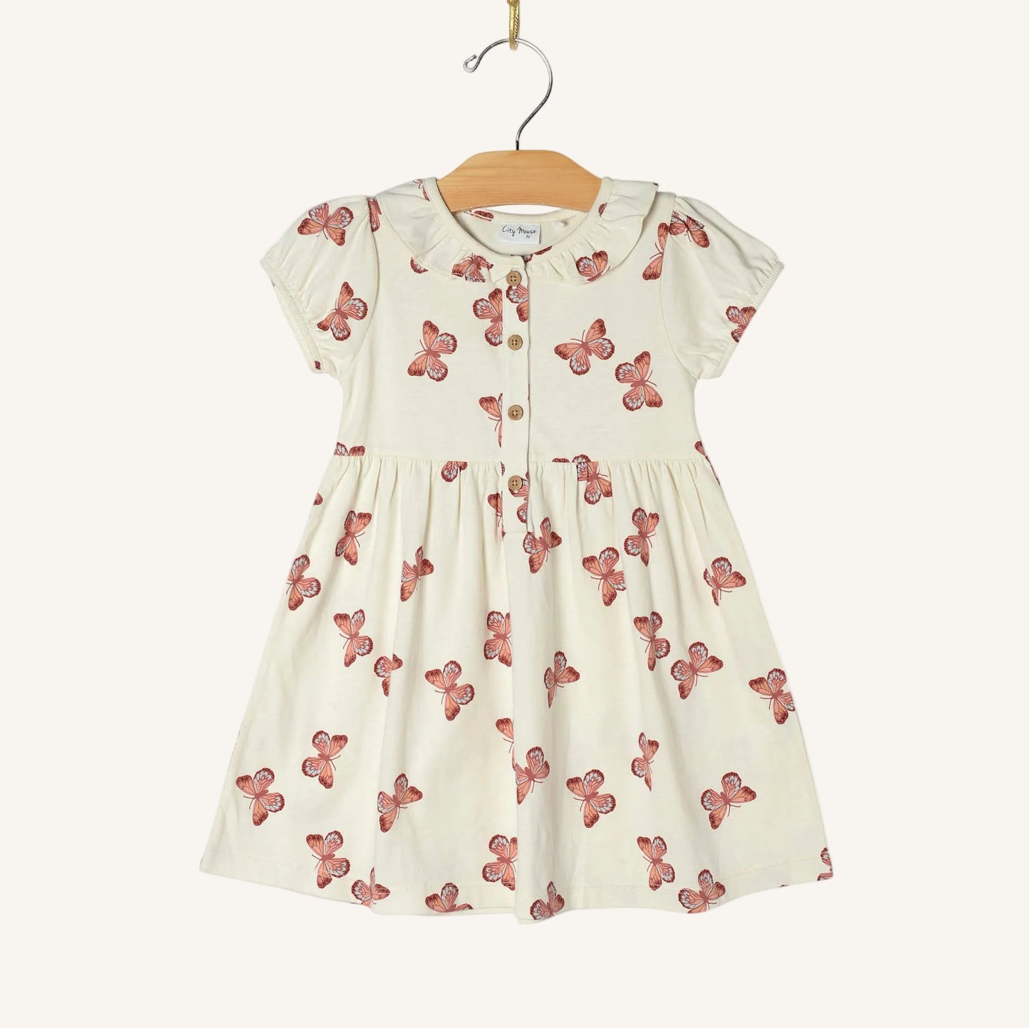 White dress with red butterfly pattern on a hanger against a white background