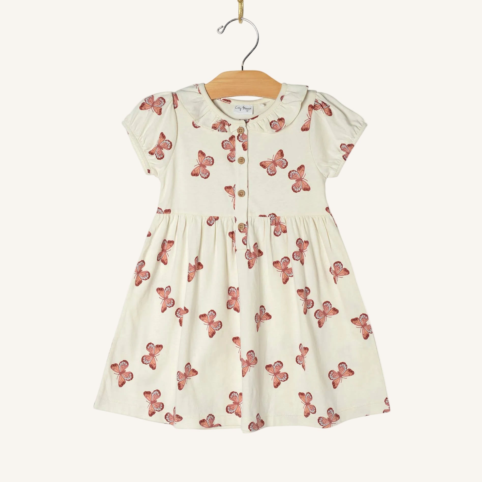 White dress with red butterfly pattern on a hanger against a white background