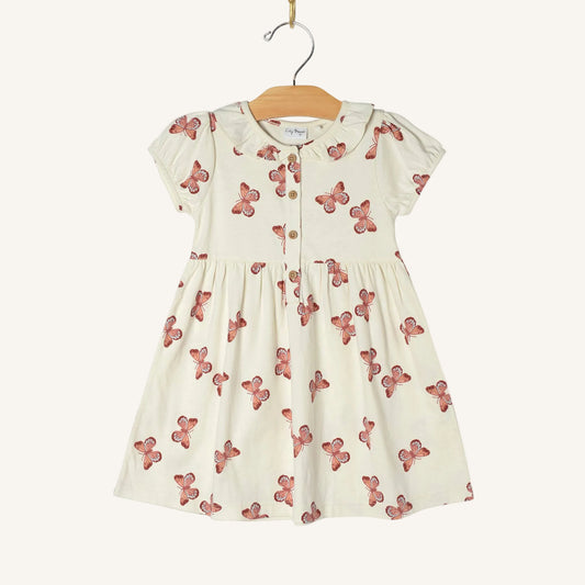 White dress with red butterfly pattern on a hanger against a white background