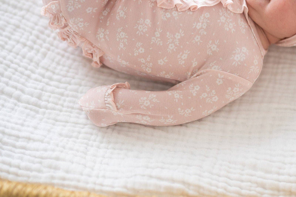 Baby in pink floral outfit lying on a textured surface