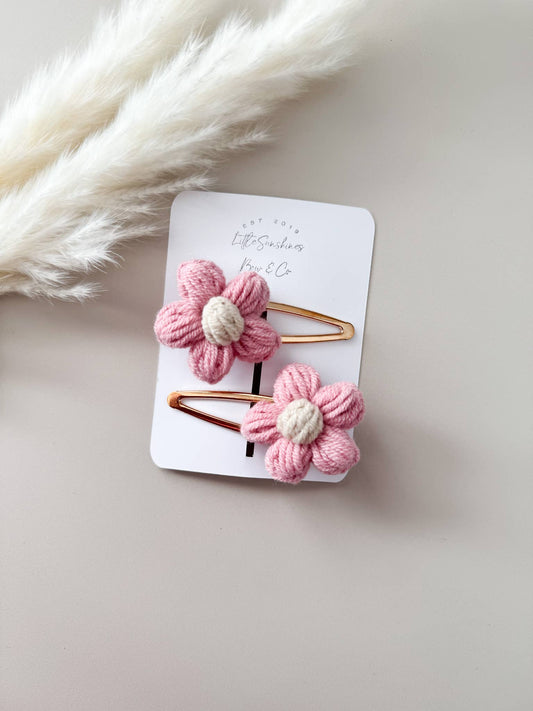 Pair of pink flower-shaped hair clips on a white card with a soft white background