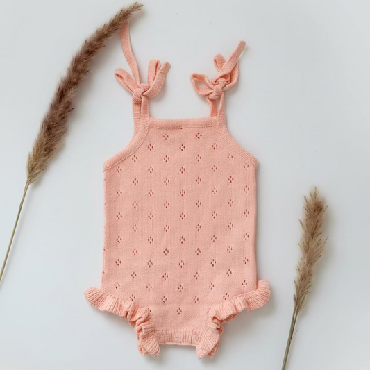 Pink knitted baby romper on a white background