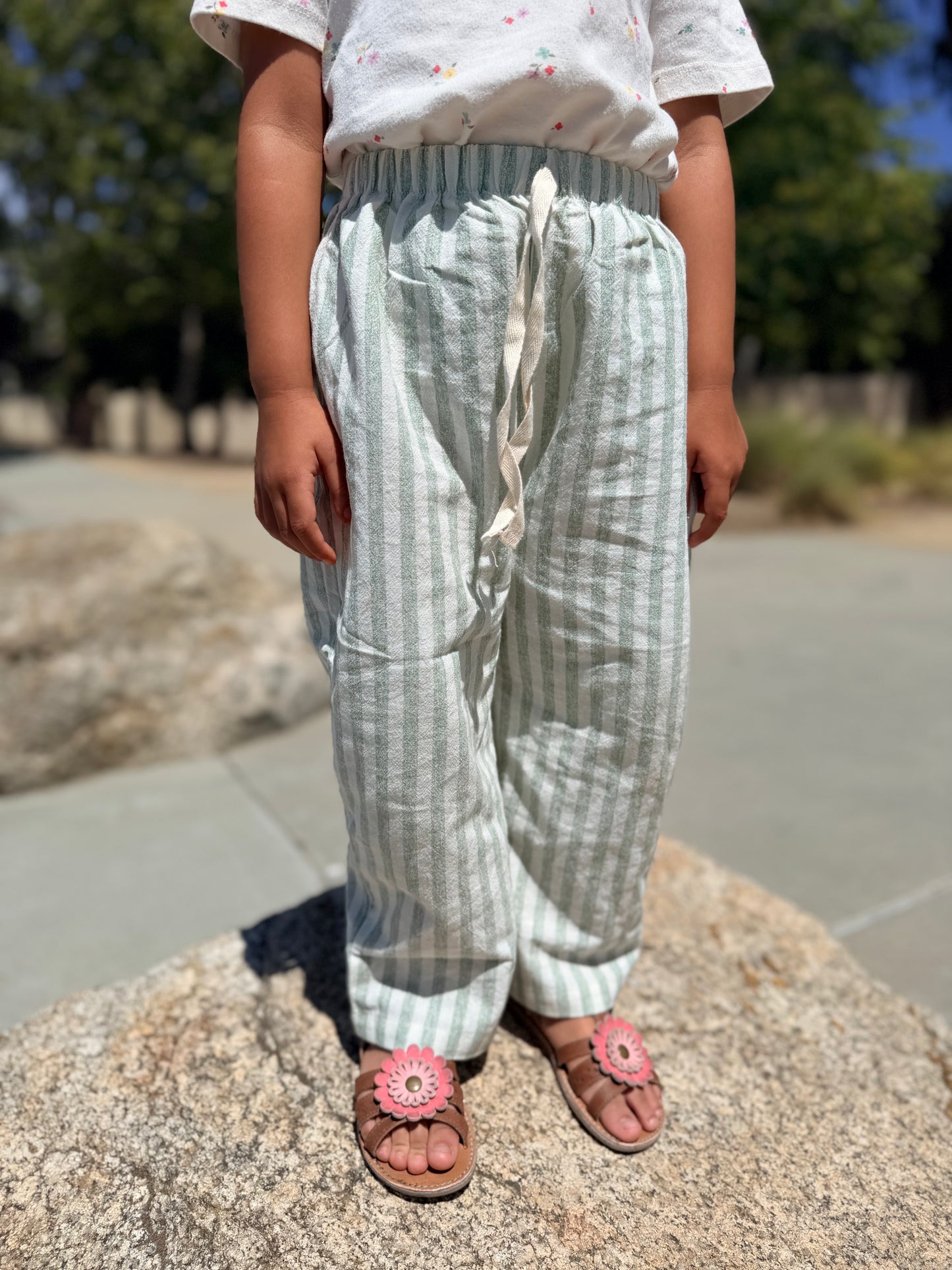 Child wearing green stripped pants with a blurred background