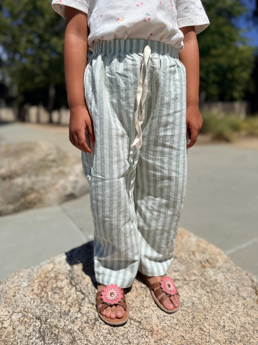 Child wearing green stripped pants with a blurred background