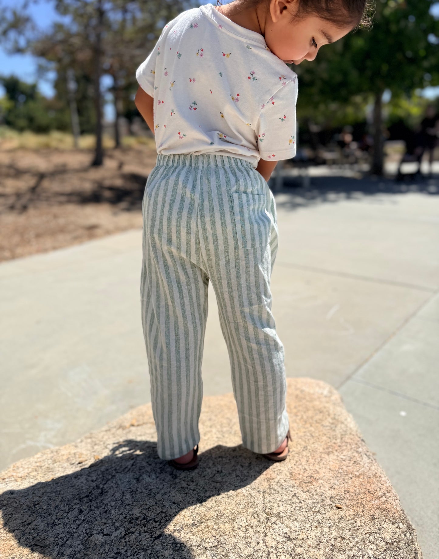 Child wearing green stripped pants with a blurred background