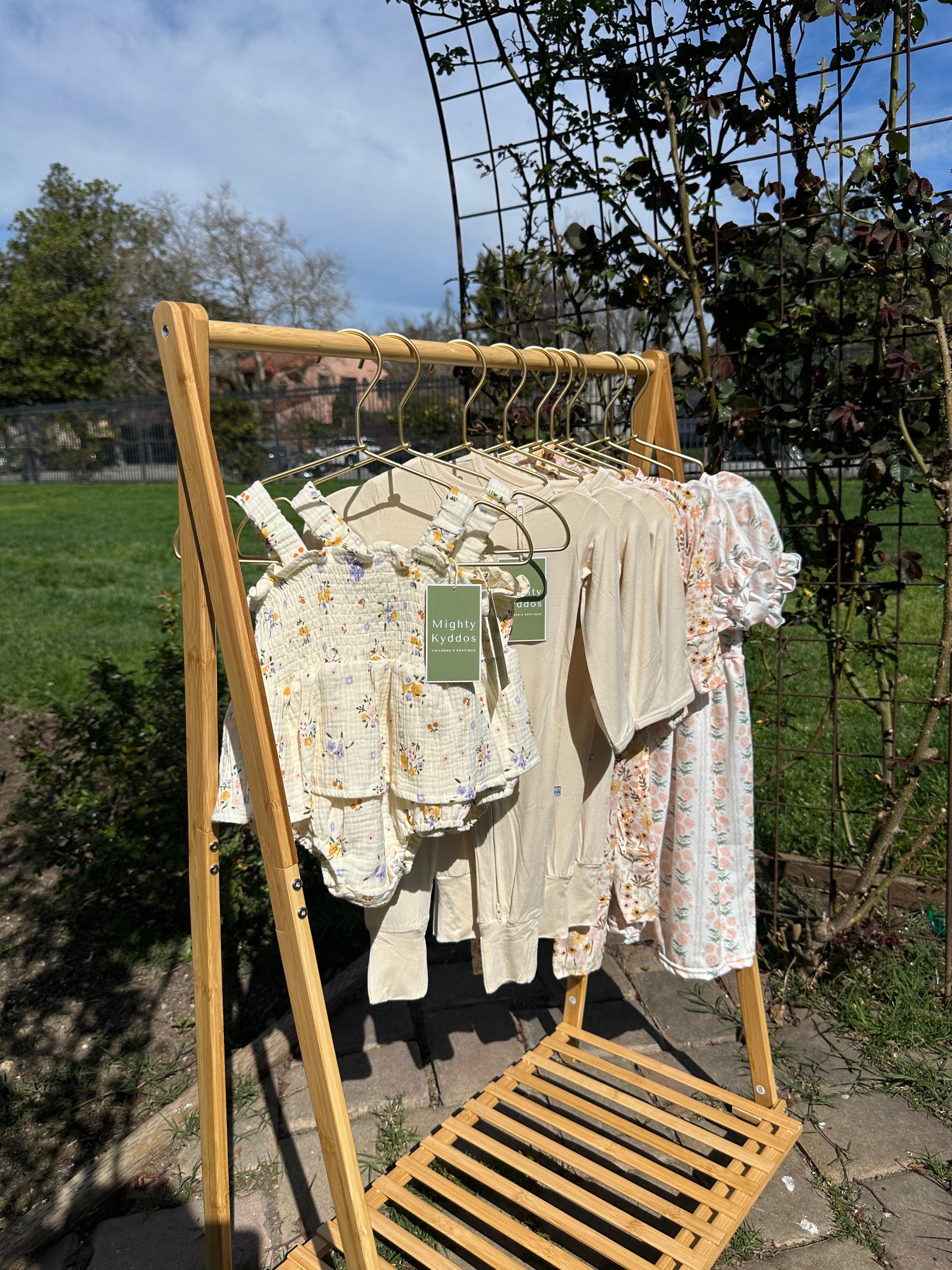 Wooden drying rack with baby clothes outdoors on a sunny day