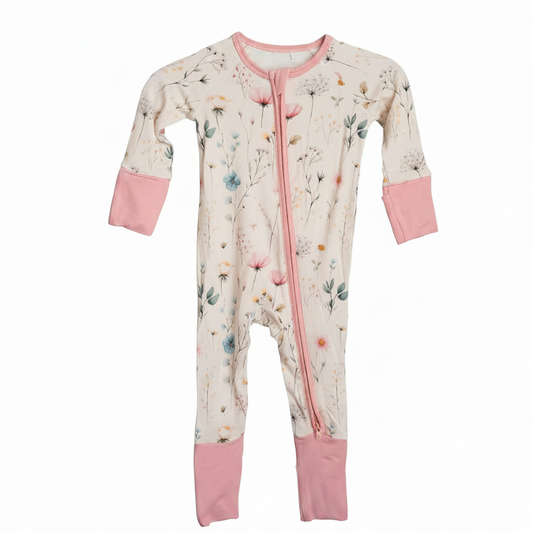 Floral-patterned baby onesie with pink accents hanging on a white rack.