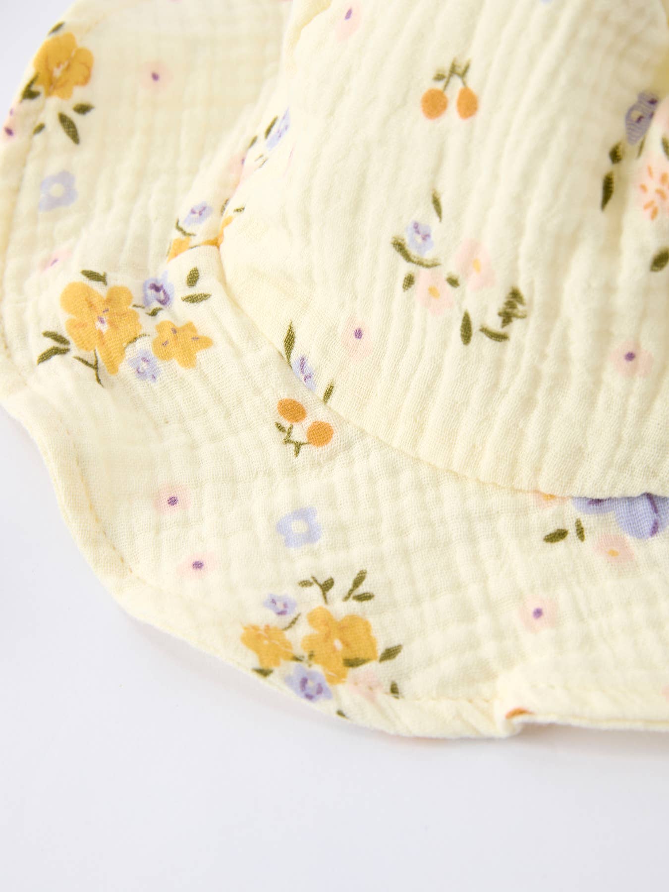 Cream-colored floral sun hat made of textured cotton gauze against a white background