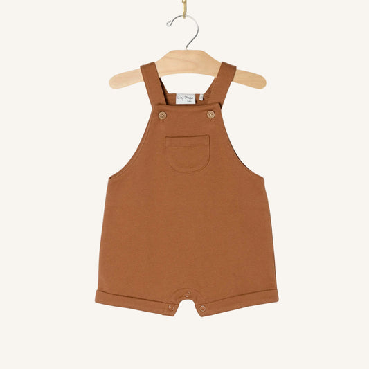 Brown children's overalls on a hanger against a white background