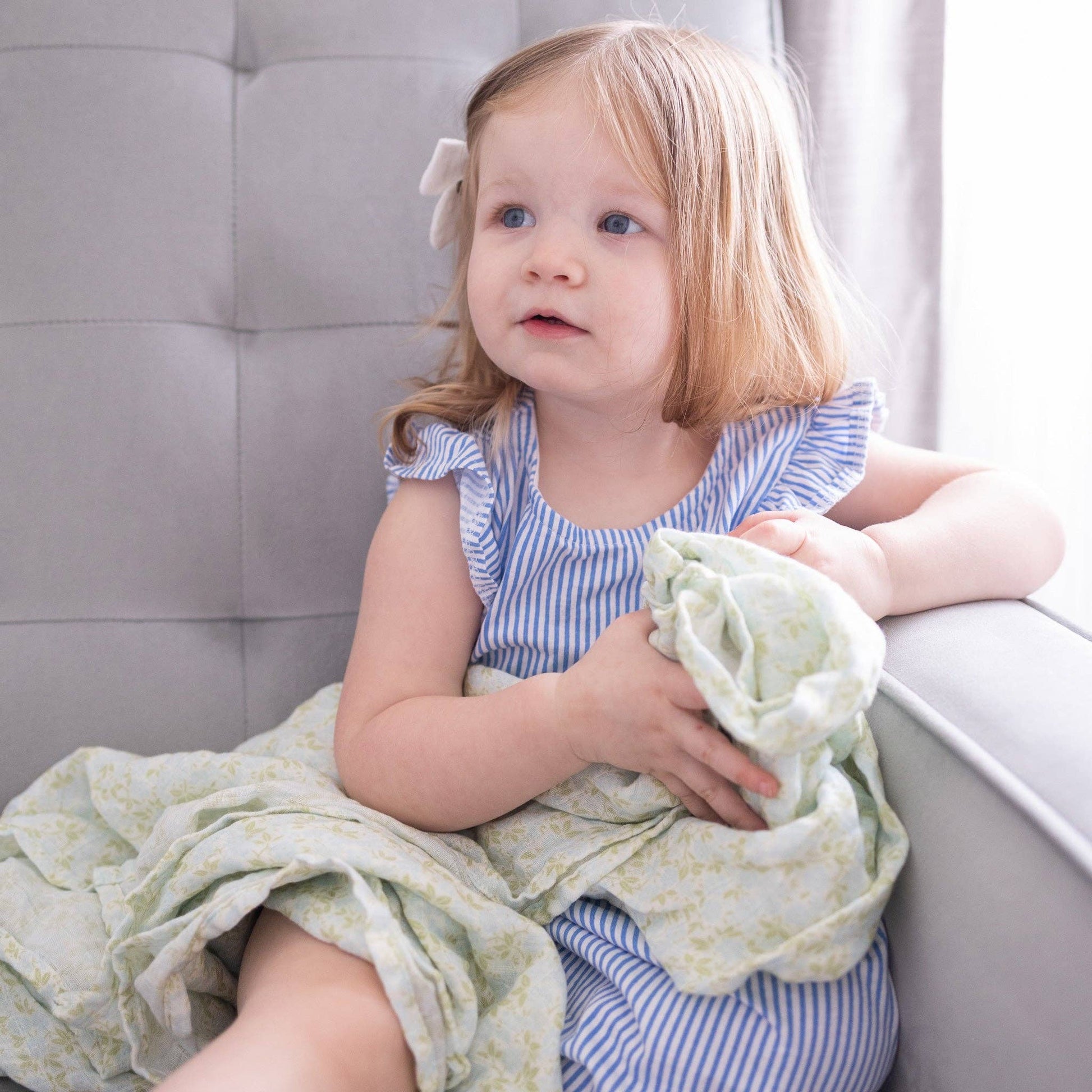 Young girl holding a green blanket in a neutral setting