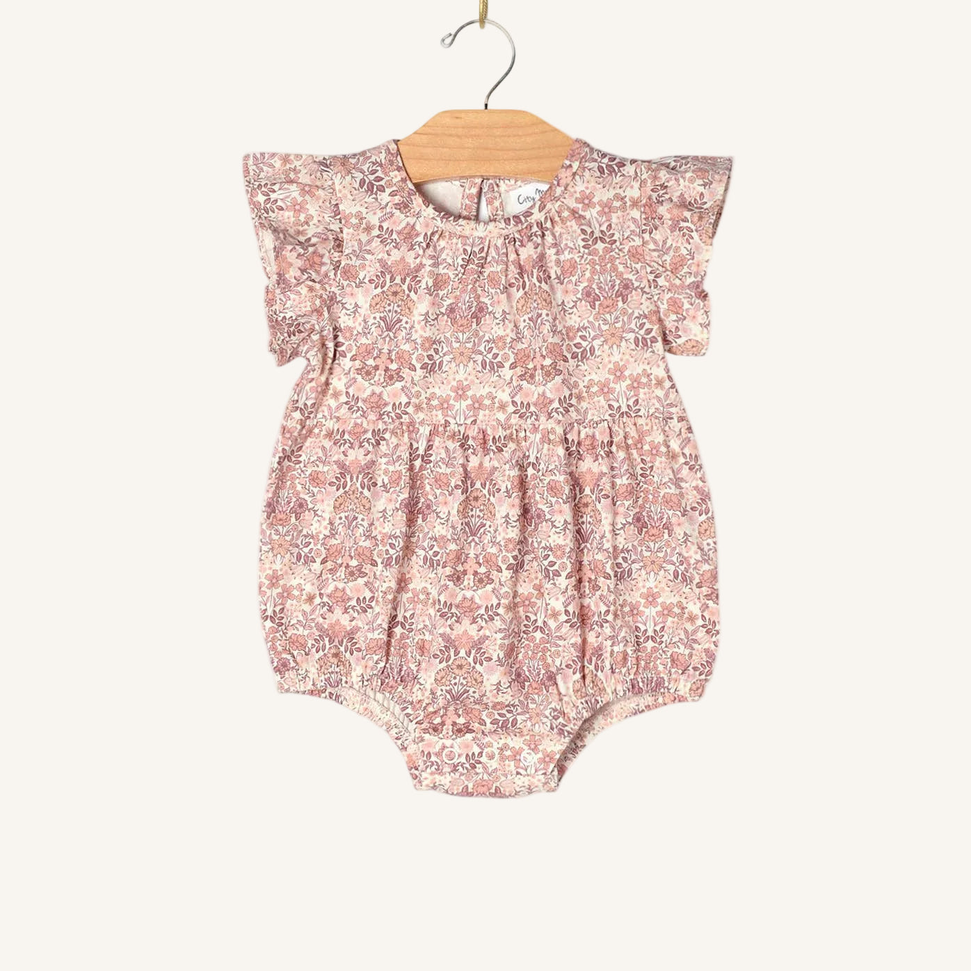 Floral baby romper on a wooden hanger against a white background