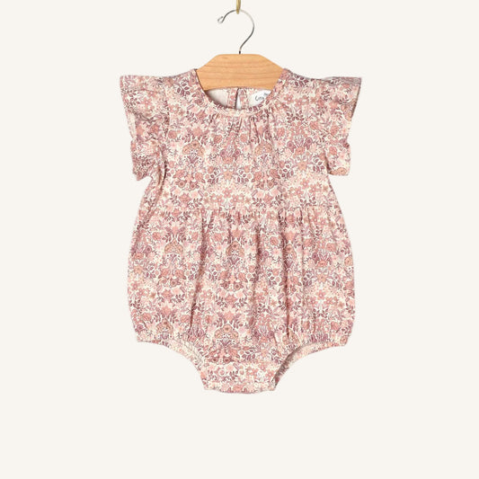 Floral baby romper on a wooden hanger against a white background